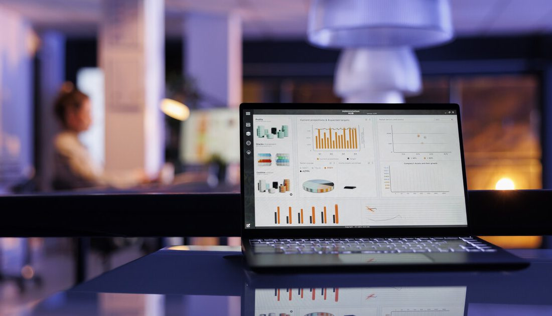 Analytics dashboard on a laptop showing profit projections and marketing ROI in a startup office