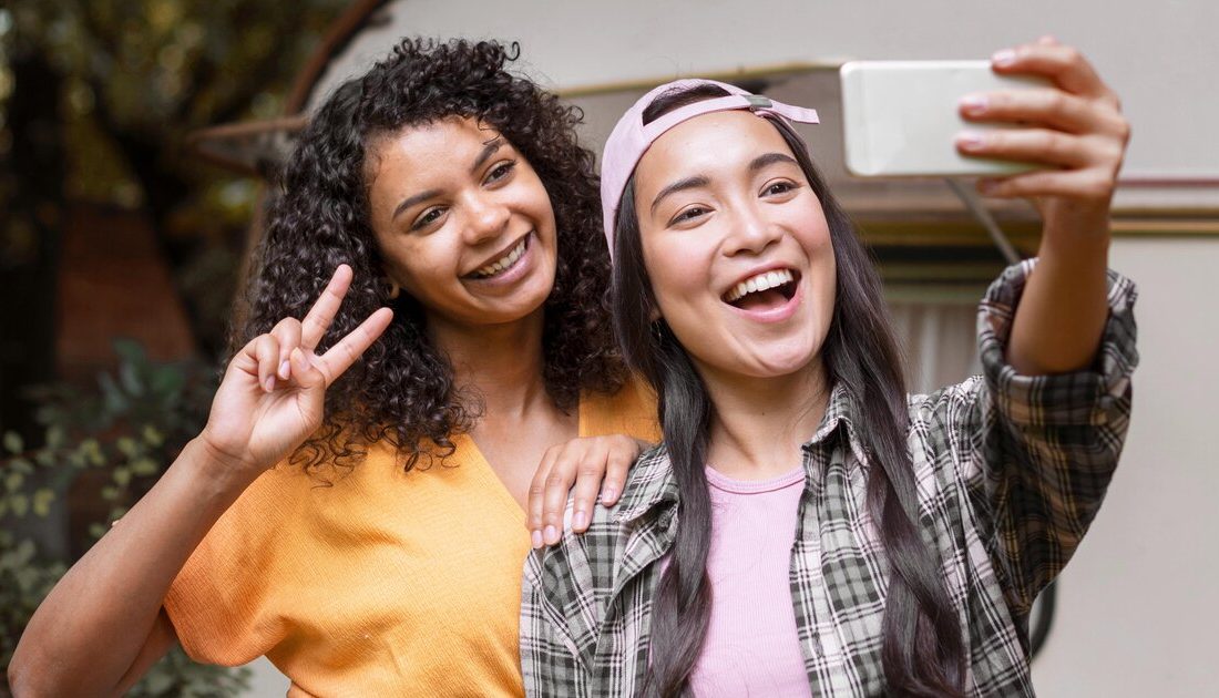 Two friends taking a candid selfie photo to share on social media
