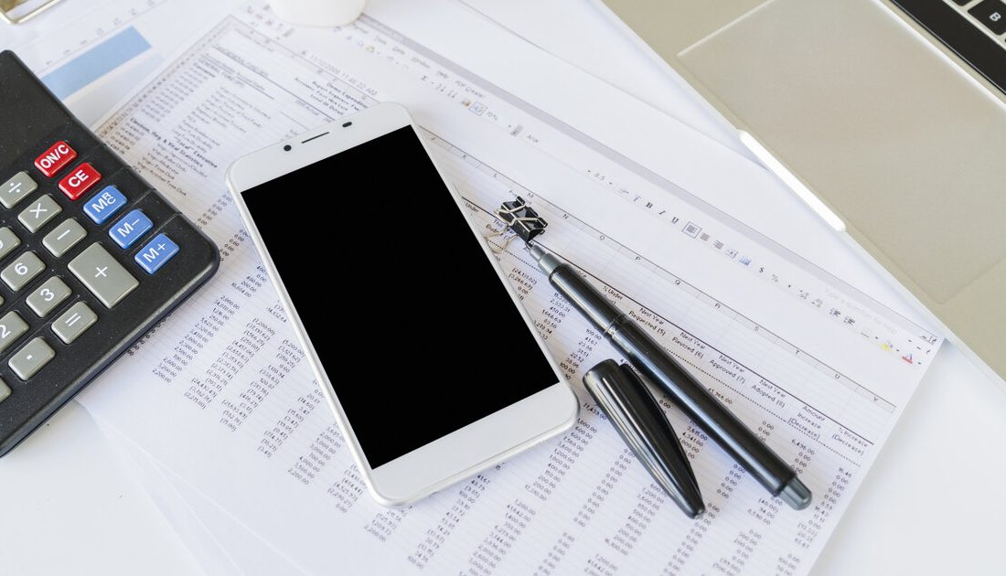 Accountant's desk with calculator, financial spreadsheets and smartphone