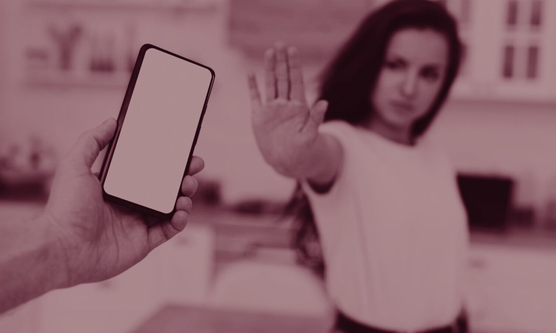 Raised palm signalling stop toward a smartphone held out by another hand, wine duotone