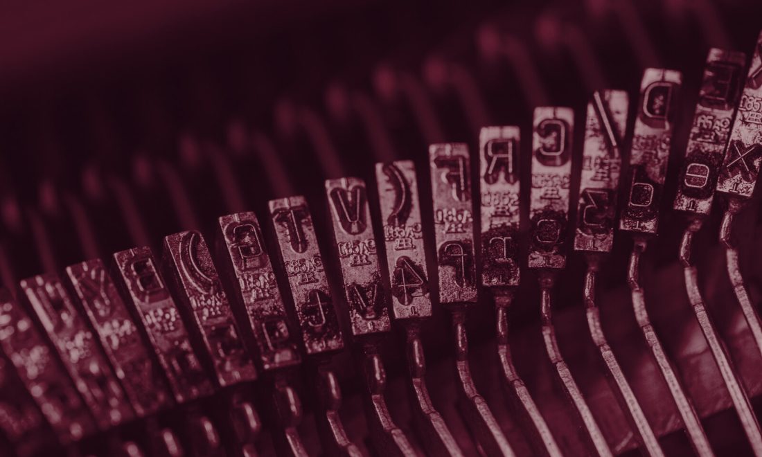 Macro view of typewriter typebars, metal letter slugs in a row, tinted deep wine red
