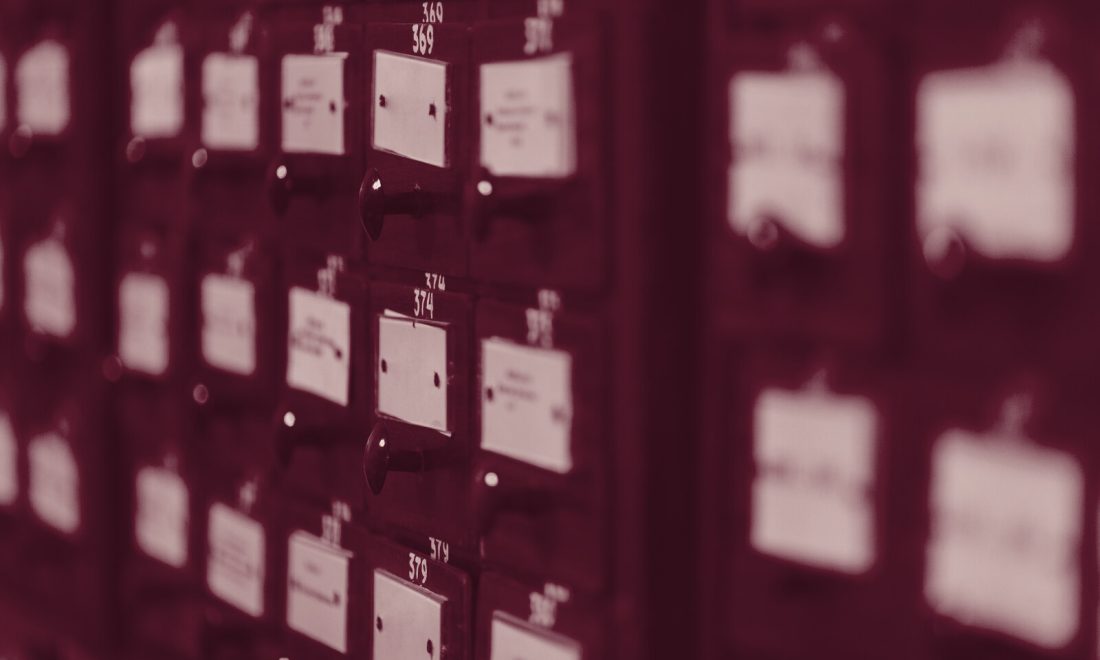 Wall of library card catalogue drawers, each identified only by a small handwritten label