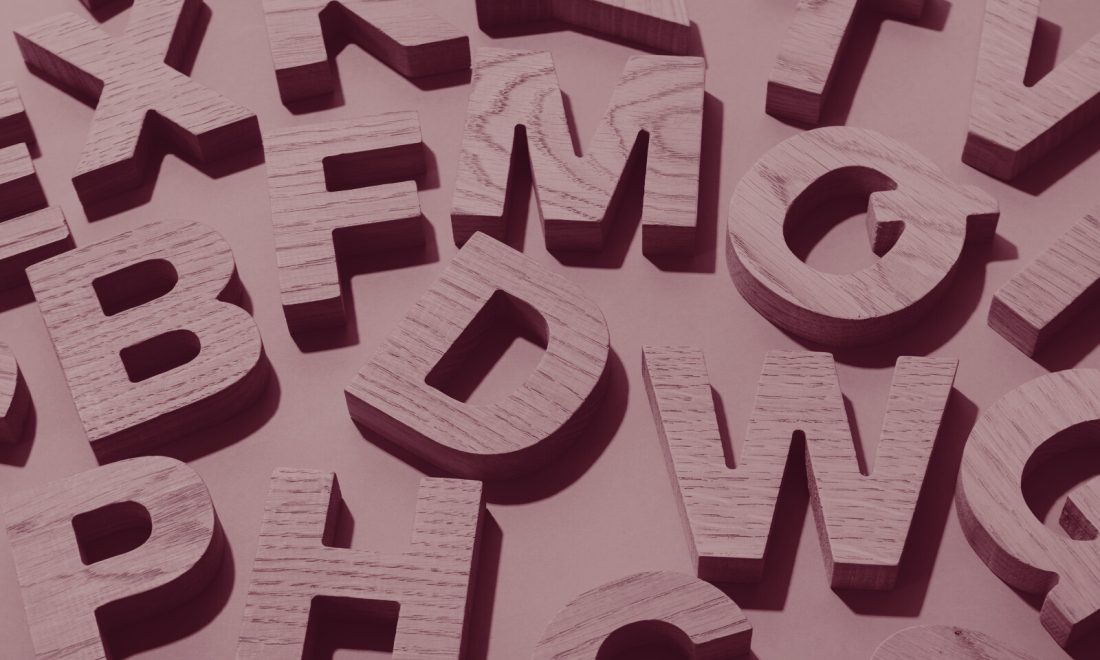 Scattered wooden alphabet letters in a wine-toned duotone