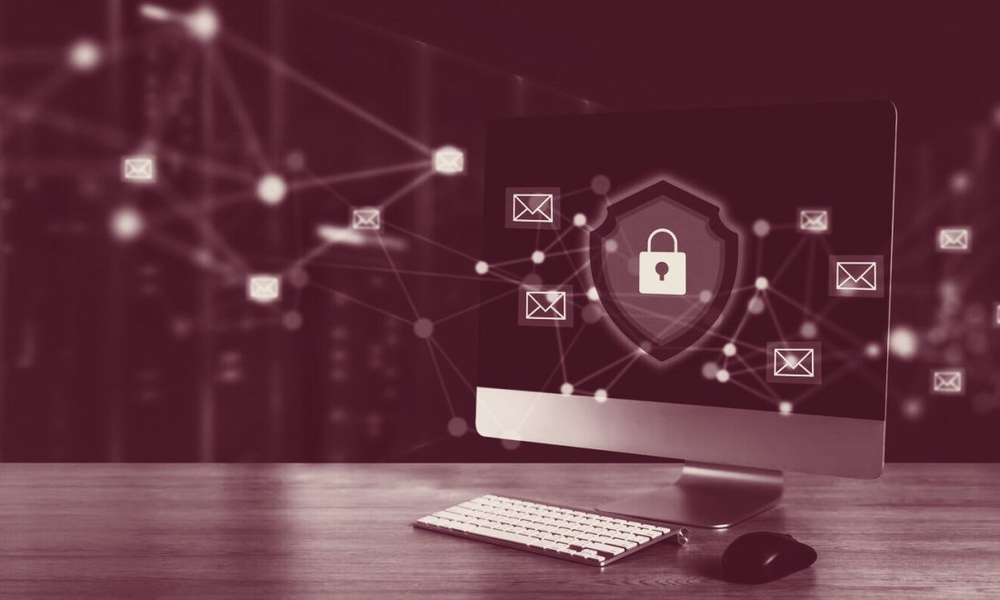 Wine-toned photo of a desktop monitor showing a padlock shield surrounded by email envelope icons